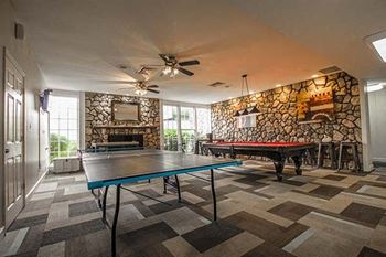 a game room with two ping pong tables and a fireplace